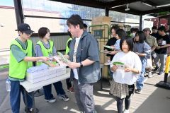 「オリジナルうちわ」などを受け取る来場者ら