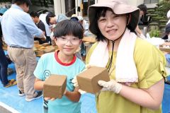 成形が完了したれんがを手に笑顔を見せる親子
