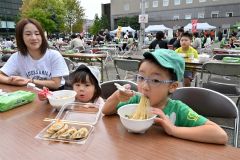 大好きなラーメンや餃子を味わう子ども（２０日午前１１時ごろ、駅北多目的広場で。金野和彦撮影）