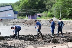 町道や歩道に溜まった汚泥をかき出す町職員
