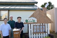 近頃作成した「集いの杜オブジェ」を横に、創作展の来場を呼びかける吉田良孝さん（写真億）とパース作家の松原宏悦さん（手前右）、妻の吉田弘子さん（手前左）