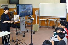 戦争関連の紙芝居を６年生に読み聞かせるブックビーンズのメンバー（左）