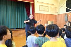 兵庫県稲美少年少女合唱団の椿野代表(中央)の合唱指導を受ける駒場小の児童ら