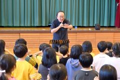 兵庫県稲美少年少女合唱団の椿野代表(中央)の合唱指導を受ける駒場小の児童ら