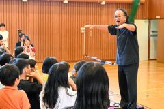 兵庫県稲美少年少女合唱団の椿野代表(右)の合唱指導を受ける駒場小の児童ら