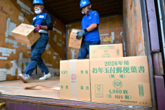 コンテナから次々と降ろされる年賀はがきが入ったダンボール箱（２日午前９時ごろ。帯広郵便局で。金野和彦撮影）