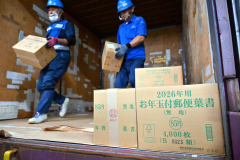 コンテナから次々と降ろされる年賀はがきが入ったダンボール箱（２日午前９時ごろ。帯広郵便局で。金野和彦撮影）