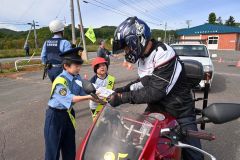 国道２４２号を通行するライダーに安全運転を呼びかける大誉地小の児童