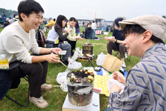 炭火台を囲み、ニンニクと十勝産の牛肉を味わう来場者（４日、午前１０時半ごろ、清水町内のホクレン清水製糖工場広場で。金野和彦撮影）