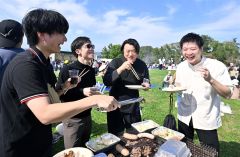 秋晴れの下、ワインを片手に食事を楽しむ来場客（５日午前１０時５０分ごろ、池田・ワイン城横イベント広場。塩原真撮影）