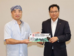 ステッカーを手にする栗原さん（左）と阿部副社長（宮坂建設工業提供）