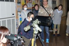 反射望遠鏡で土星の映像を観察する参加者
