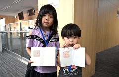 海外旅行模擬体験ツアーで仮想パスポートに出国スタンプを押してもらった子ども（須貝拓也撮影）