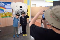 パイロットの制服を着てマスコットと記念撮影する子ども（須貝拓也撮影）
