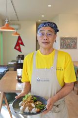ネパールカレーを手に持ち、「幅広い人たちの集まる場になれば」と話す小泉さん