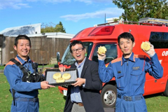 「消防メロンパン」を手に火災予防を呼び掛ける、満寿屋商店の大川原さん（中央）と帯広消防署の署員ら