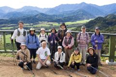 山頂展望台まで歩き、日高山脈の雄大な景色をバックに記念撮影する参加者ら