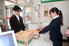 ぽすちょこ便を活用して届いた野菜を窓口で受け取る町民（左）