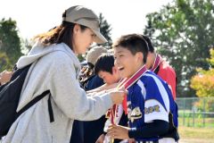 メダルをかけてもらい、うれしそうな表情を浮かべる選手