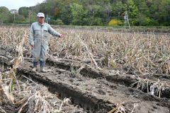大量の土砂が流れ込みトウモロコシが冠水した畑で被害状況を語る元木さん（１７日）