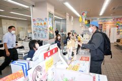 無言で現金を要求する犯人役の署員（右）に対応する局員たち