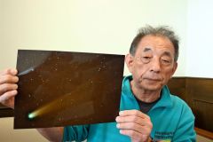 ２０日に撮影したレモン彗星の写真を手にする田巻さん