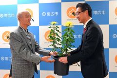 米沢市長（右）に菊を手渡す高井会長