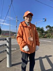 子どもたちの見守りで国道242号交差点に20年立つ田西昭子さん(写真左)
