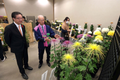 菊について解説する帯広菊花同好会の高井信夫会長(中央)と、耳を傾ける米沢則寿帯広市長(左)(助川かおる通信員撮影)