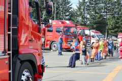 消防車と綱引きする参加者ら