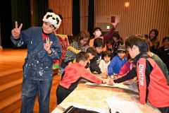 バレンを手に版画の仕上げ作業に挑戦する来場者と石村さん(左)