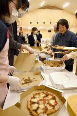 新鮮野菜をトッピングしたピザの提供を受ける参加者ら