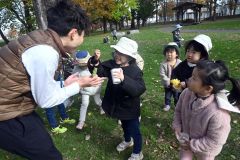見つけた植物を職員に見せる園児