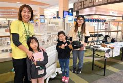 初展示となった保育器の前で活動をＰＲする（右から）高橋さんと愛乃ちゃん、悠愛ちゃんと小倉さん（１４日の展示会で）