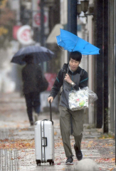 傘が反転する横なぎの風に耐える歩行者(1日午前10時20分ごろ、帯広市西2南12で。塩原真撮影)