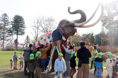 ナウマンゾウの親子模型にブランケットとマフラーを取り付ける園児ら