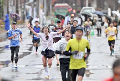 両手を上げてゴールに入るランナー。悪天候ながら沿道の観客も声援を送った（２日午前１０時すぎ、塩原真撮影）