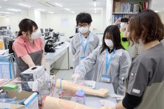 精巧な腕のダミーを使って採血の方法を学ぶ参加者