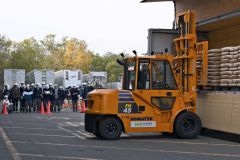 トラックから砂糖をフォークリフトで運び出す様子を見学する生徒たち