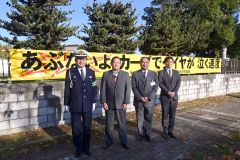 一新した横断幕と関係者。右端が遊佐会長