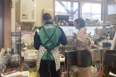 中学生に洗い物の方法などを教える座間店主