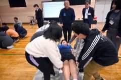 保温用アルミシートを用いた応急担架搬送を体験する子どもたち