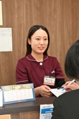 受付に立ち笑顔で問診票を手渡す久保さん