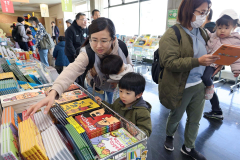 絵本を手に取る家族連れ(助川かおる通信員撮影)