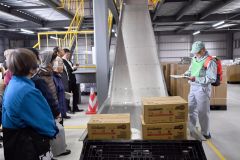 新たに完成した防災備蓄庫内で設備を解説する鈴木さん（右）と見学する町民ら