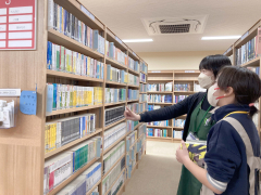 司書の井上さんから配架業務を教わる佐藤さん