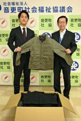 高橋専務（左）から防寒着を受ける町社協の石川事務局長（右）