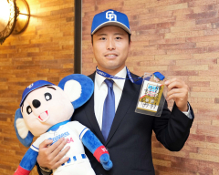 球団マスコットを抱き井上監督からのメッセージを手にする牧野憲伸＝新潟市内のホテル（大賀章好撮影）