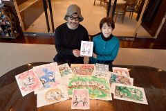 絵本を手にする（右から）もとしたさんときくちさん。机に並ぶのは、きくちさんが描いたシマエナガの原画