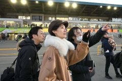 説明を聞きながらばんえい競馬のレース観戦を体験するアンジーさん（中央）